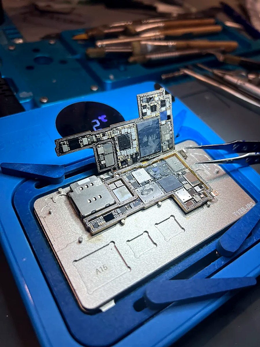 Zerlegtes iPhone-Mainboard mit A15-Chip auf einer Platinen-Schablone an der Werkbank