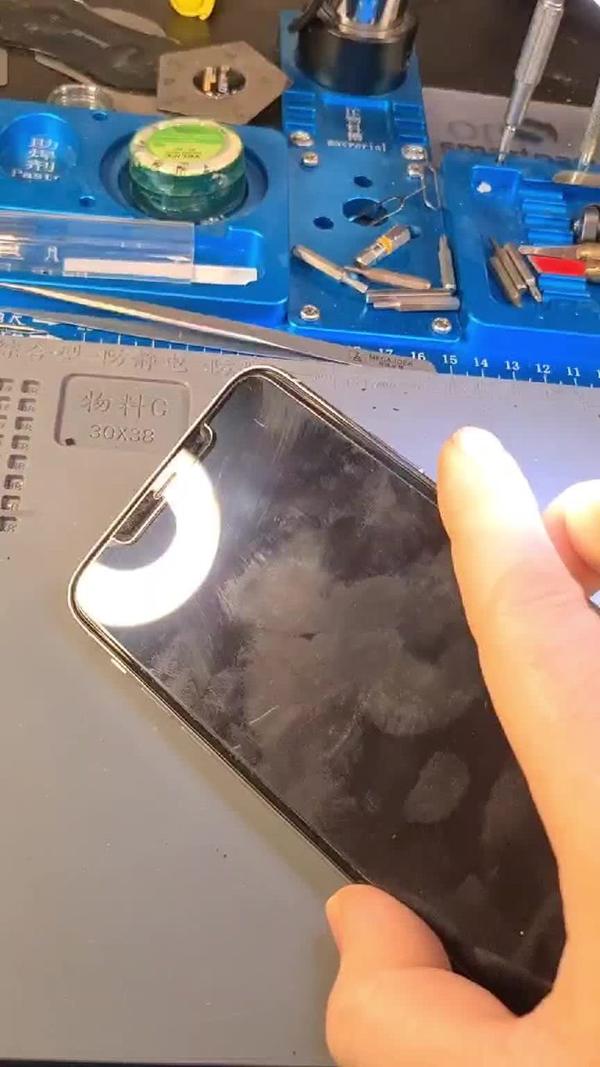 iPhone 11 Pro Max mit schwarzem Bildschirm auf der Werkbank vor Mikroskop und Werkzeug